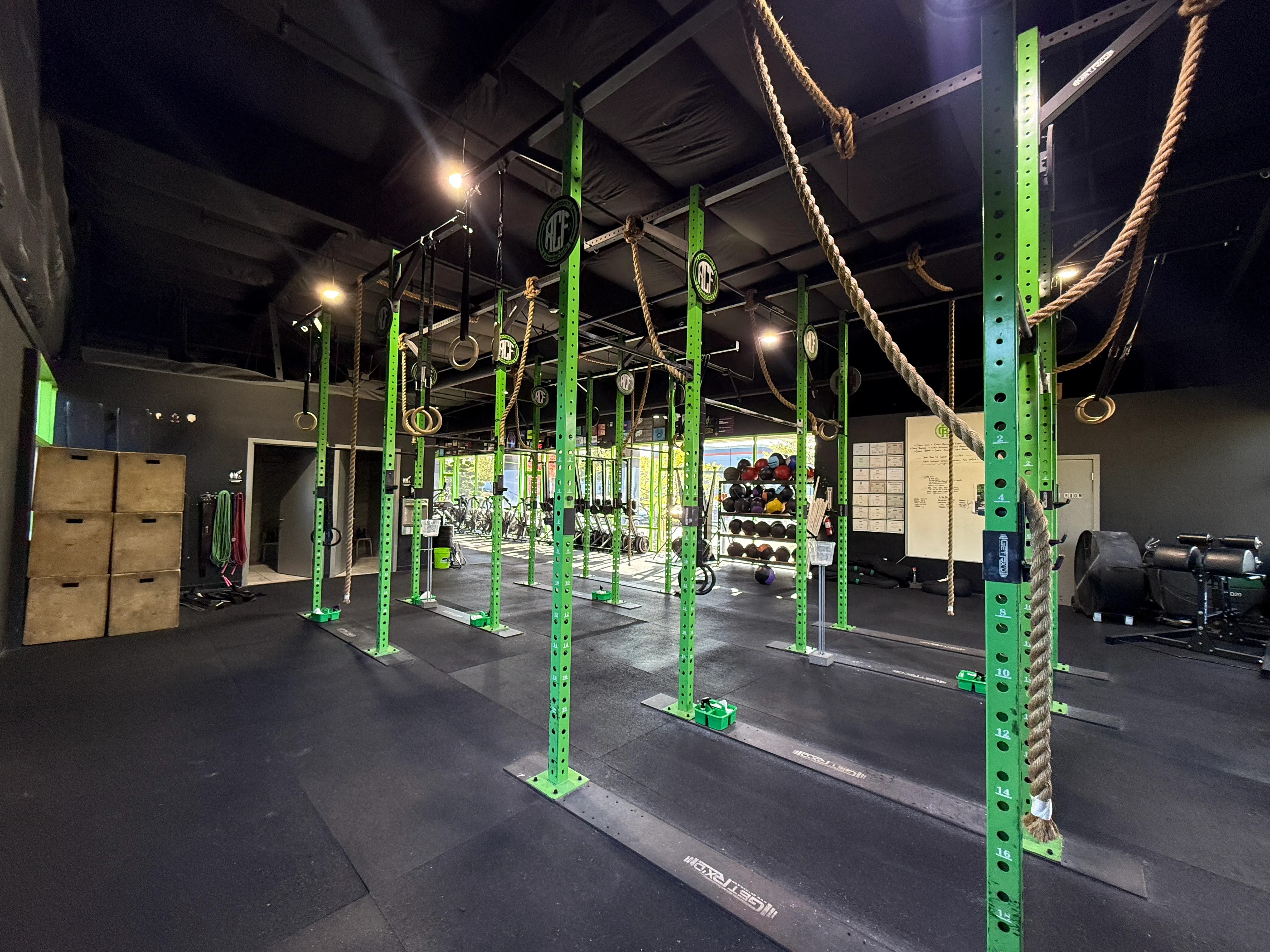 Wide view of The Hybrid Athlete Co. gym: turf lane, lifting platforms, cardio, and HYROX Training Club branding.